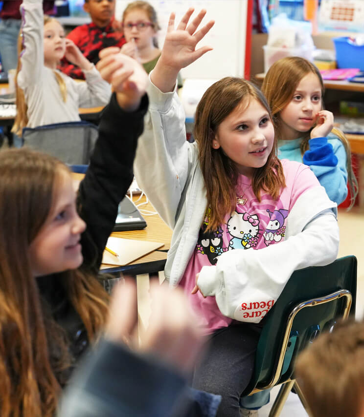 Kids in classroom raising hands